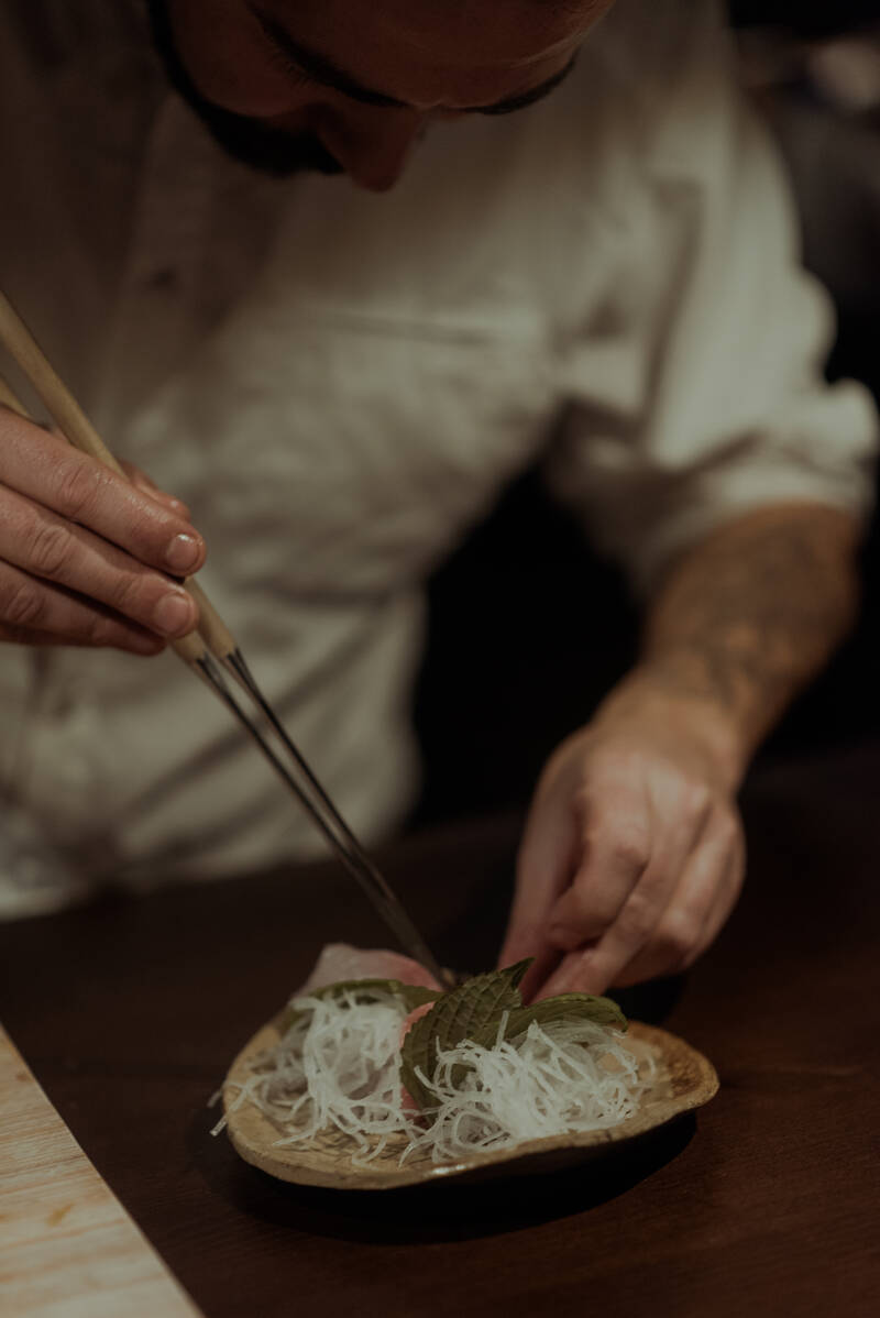 Chef a preparar prato com hashis e folha de shiso